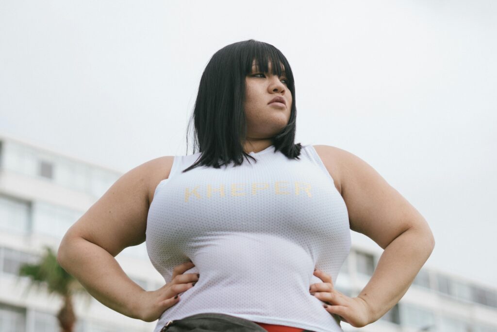 A confident plus-size model posing outdoors with hands on hips, embodying fashion and strength.